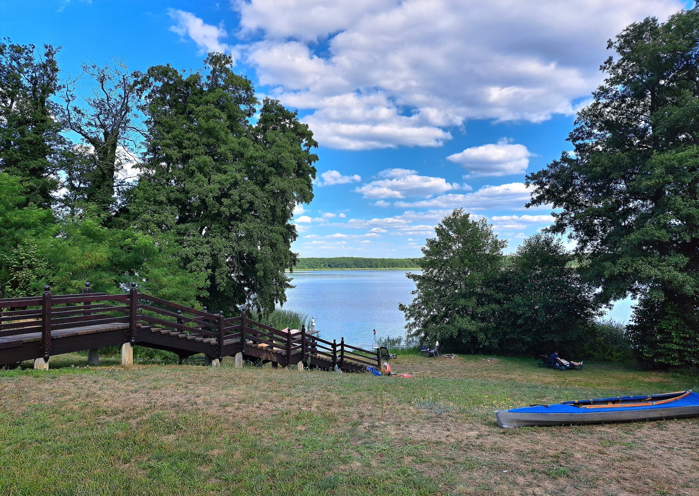 Badestelle am Mellensee mit Holzsteg, Bäumen und einem Kajak am Ufer